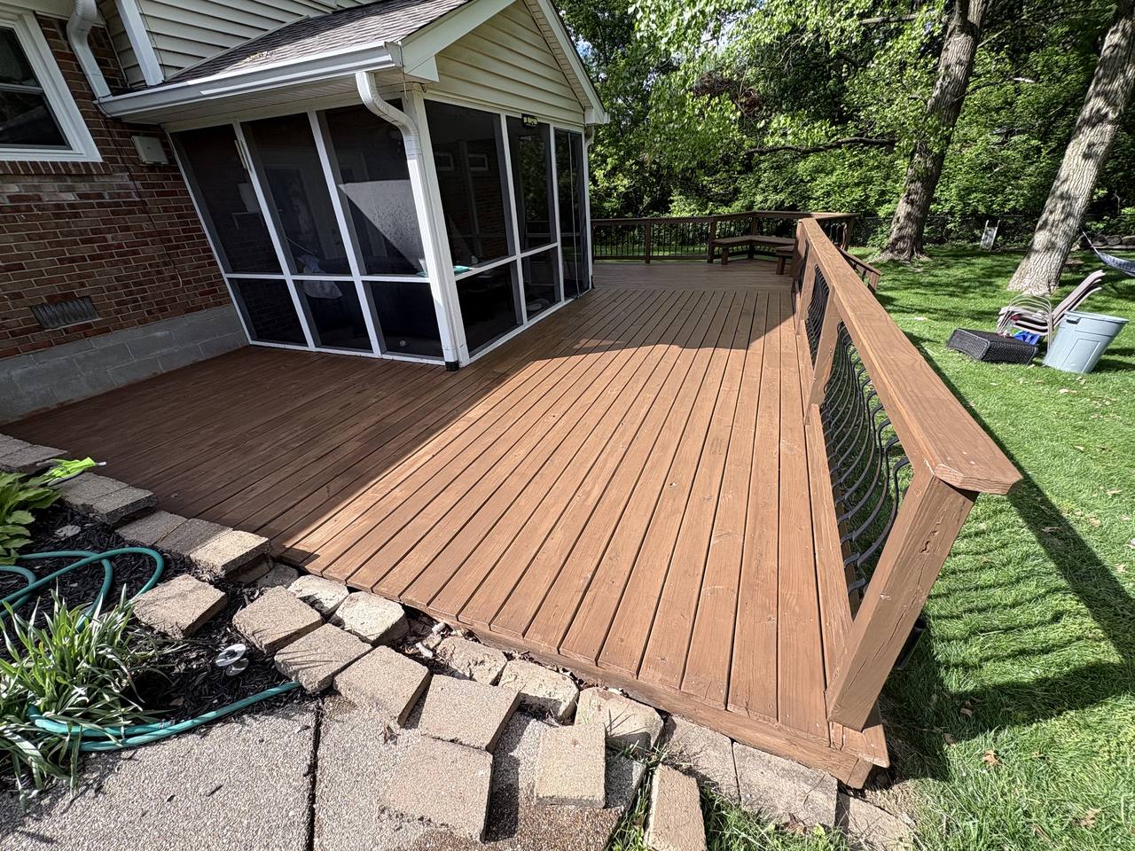 The same deck after staining, boards a deep even brown against the screened porch