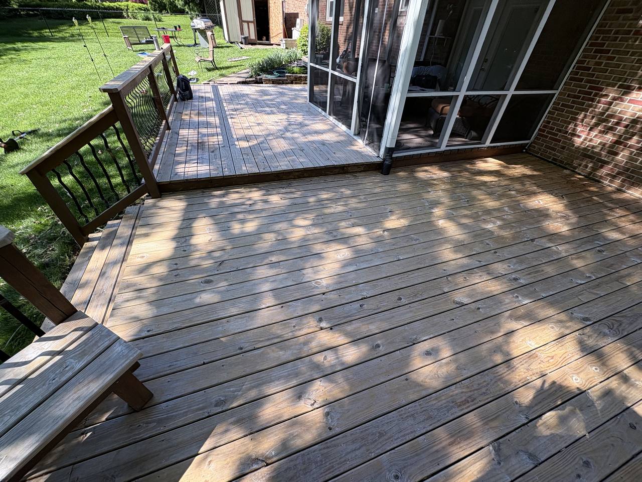 Large grey weathered deck outside a screened porch, boards faded and streaked