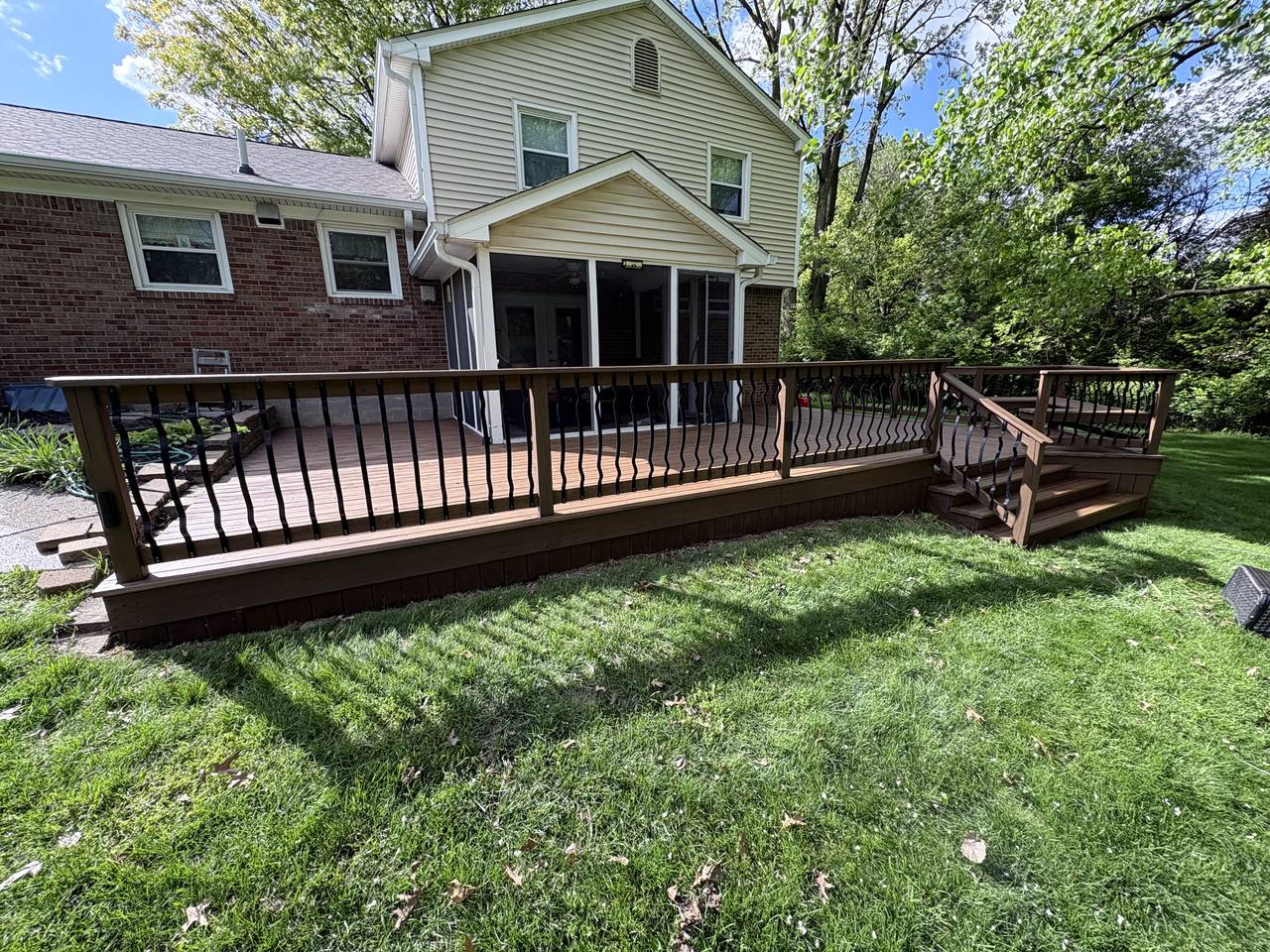 The finished deck seen from the lawn, fully stained warm brown with black railings
