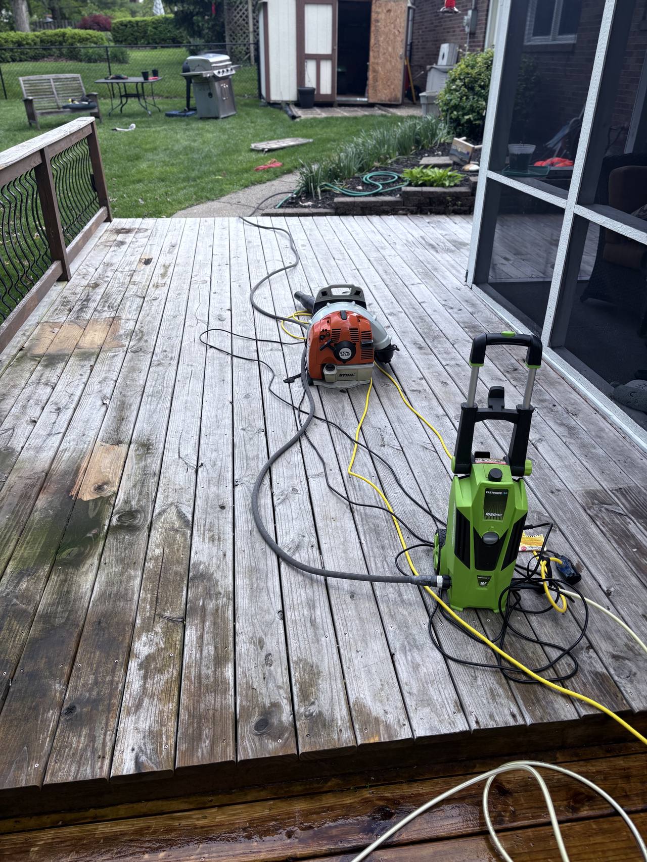 Pressure washer and backpack blower set up on a weathered grey deck